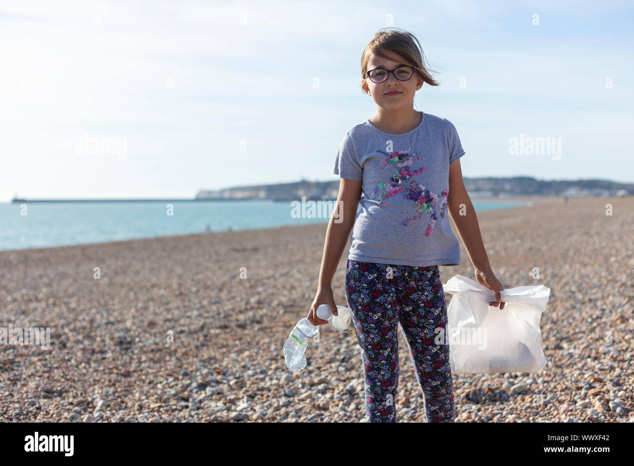 A girl picking up discarded plastic litter on a UK beach Stock Photo