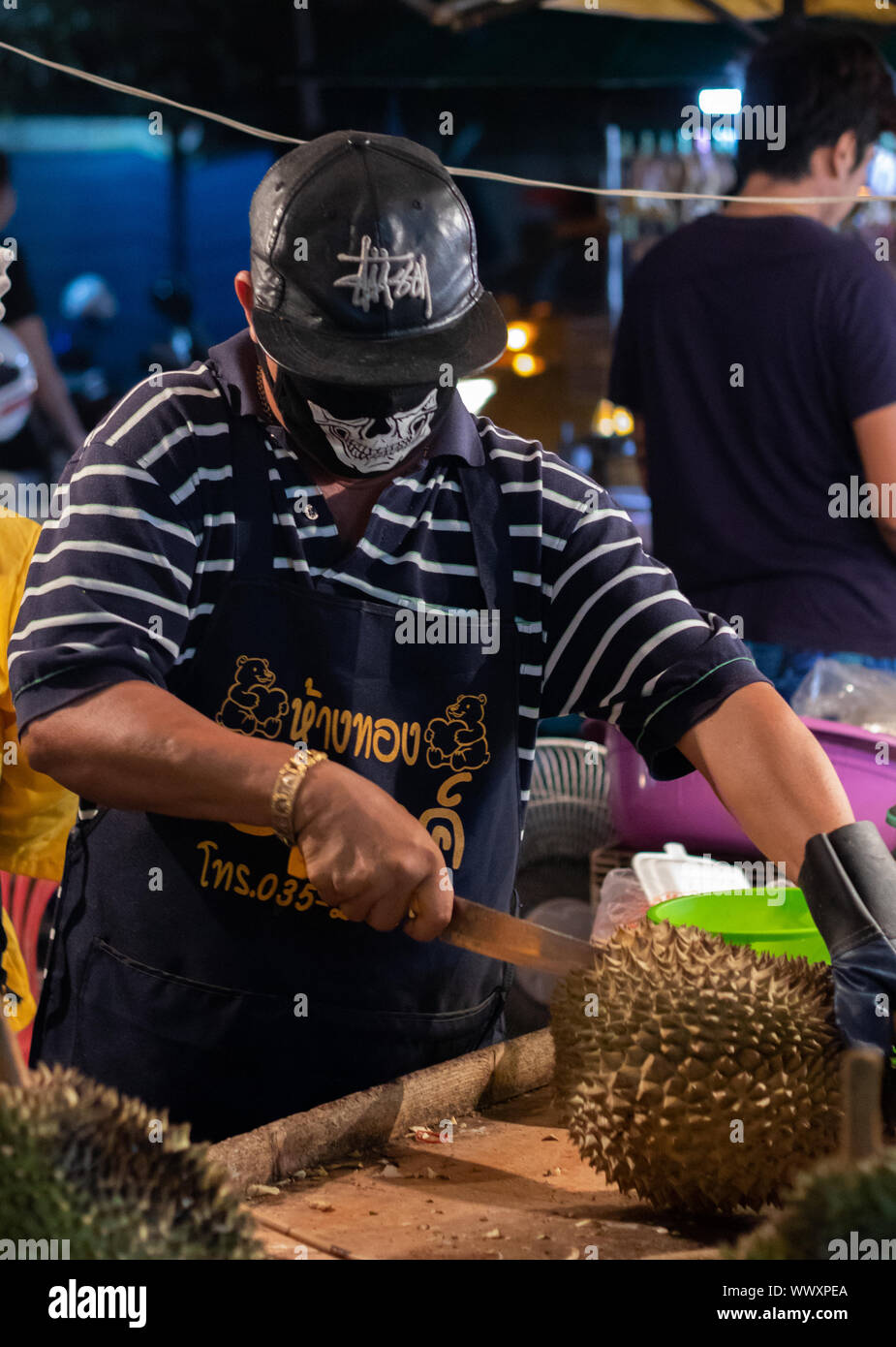 A man chops up durian fruit in a Thailand night market Stock Photo