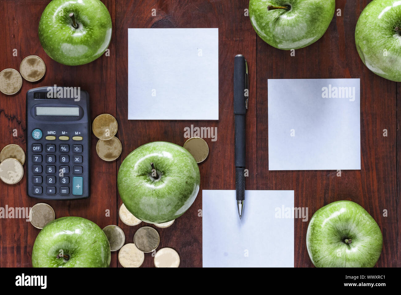 The concept: business, investment, enrichment. Green apples, gold coins, calculator and paper for en Stock Photo