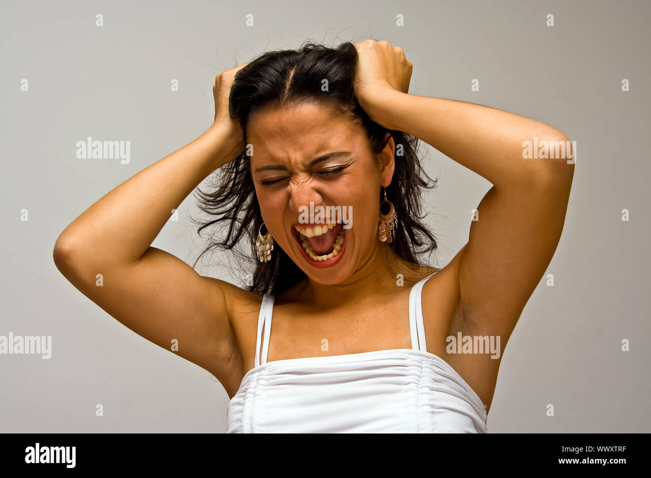 A Young Beautiful Latina Woman Screeming Of Frustration And Pulling Her Hair With Both Hands 