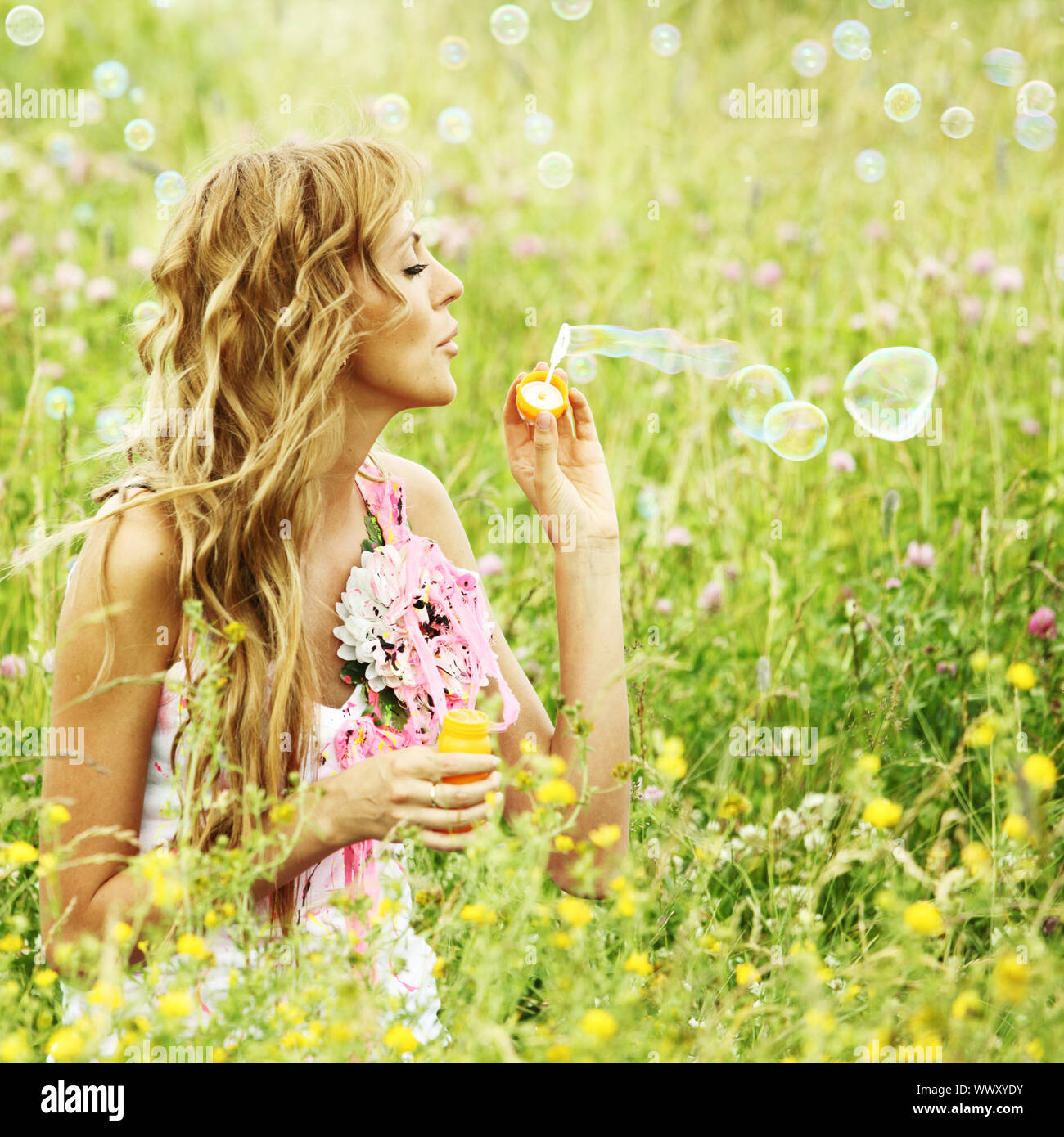Blonde starts soap bubbles in a green field Stock Photo - Alamy