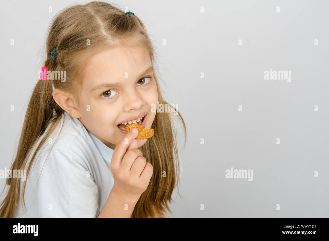Portrait of a little six year old girl biting a cookie Stock Photo