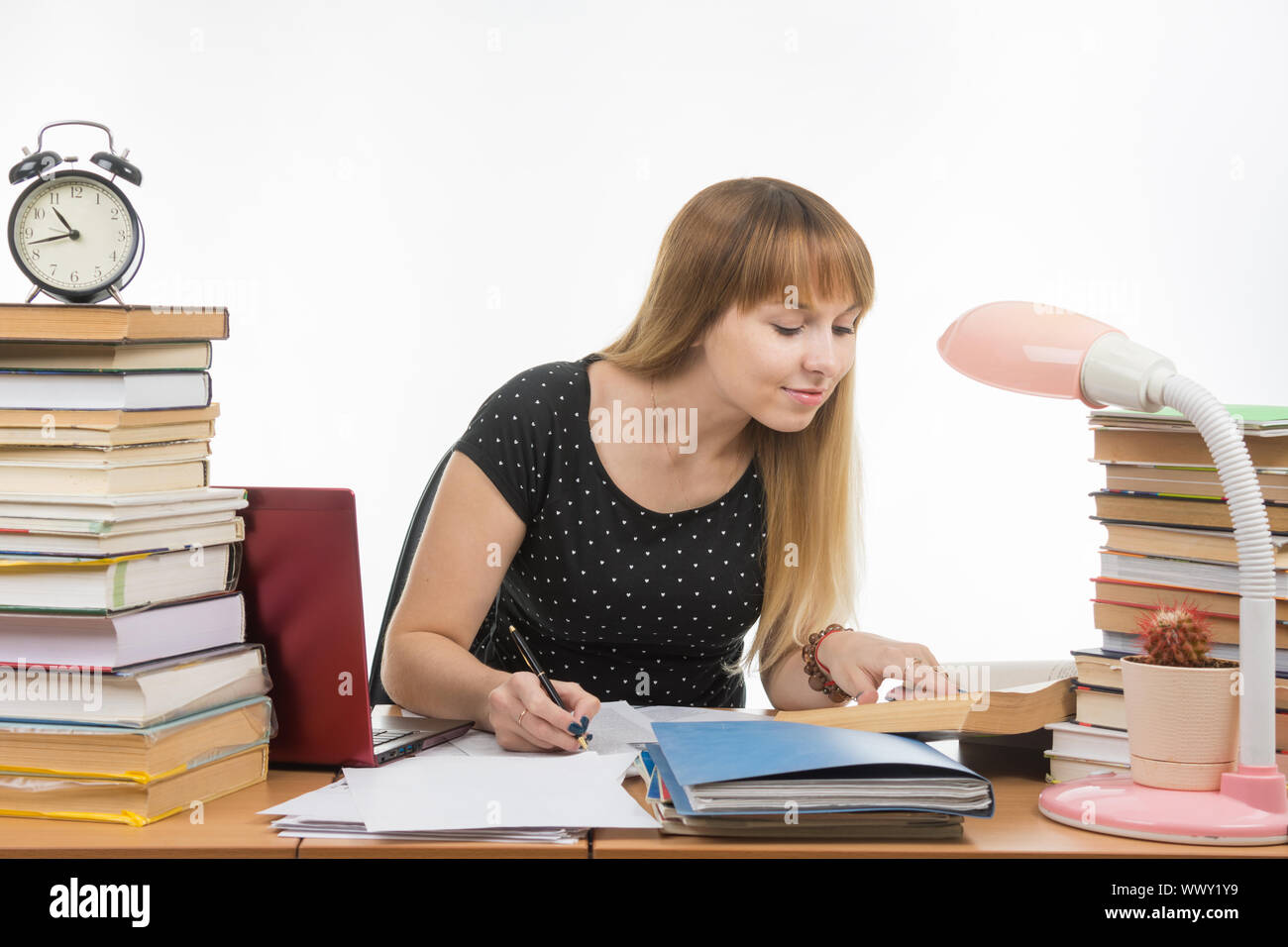Pretty female student at a table littered with books in the library