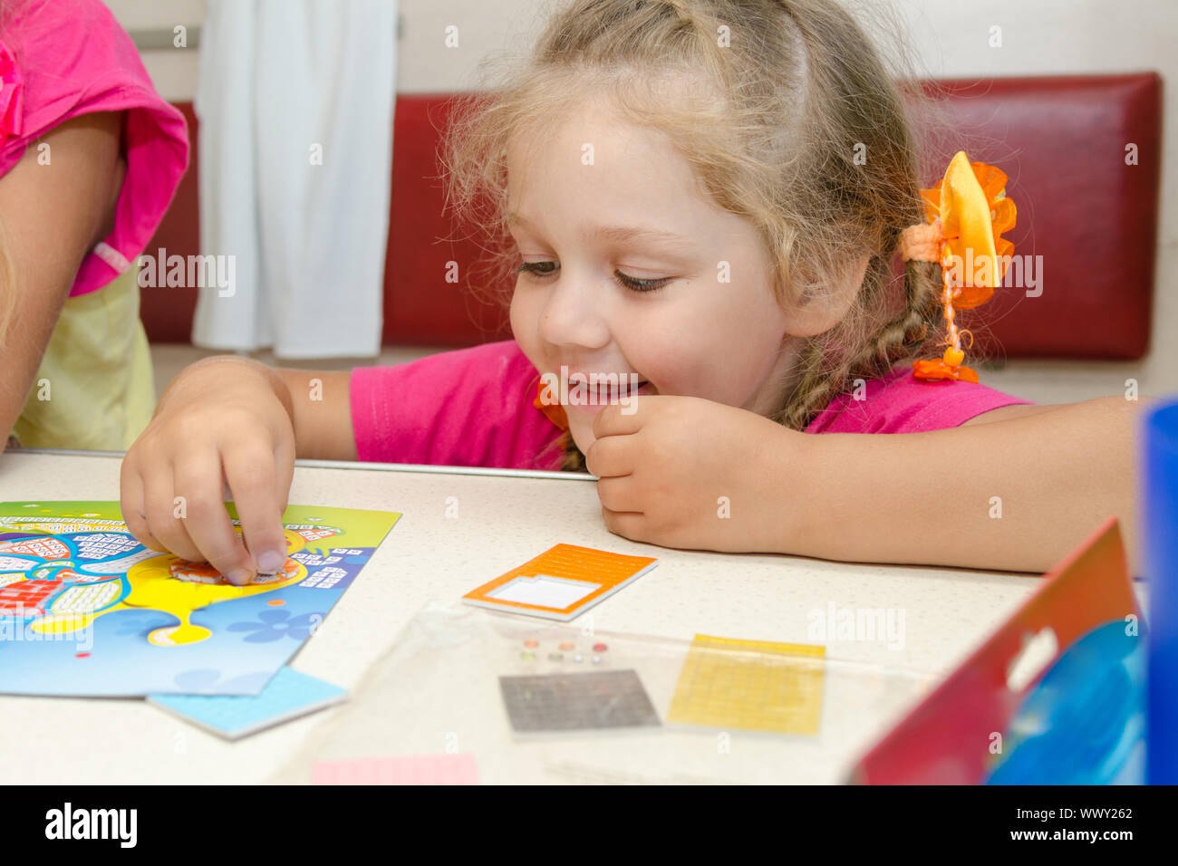 Four-year girl on a train sitting at the table on the lower second-class place car and enthusiastically plays Stock Photo