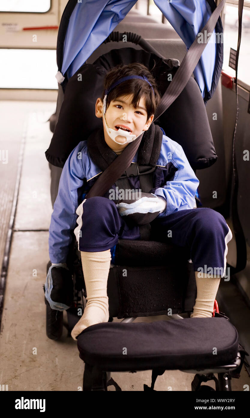 Disabled little preschool boy in wheelchair on bus. Child has cerebral palsy. Stock Photo