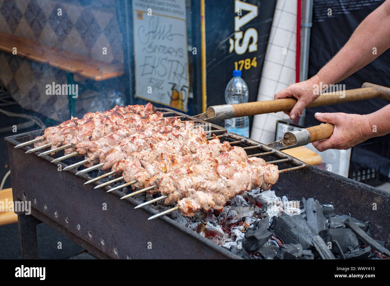 Close up of  meat skewer, grilled in a barbecue, shashlik or shashlyk of pork for a pic nic, man preparing and roasting with pitchforks Stock Photo