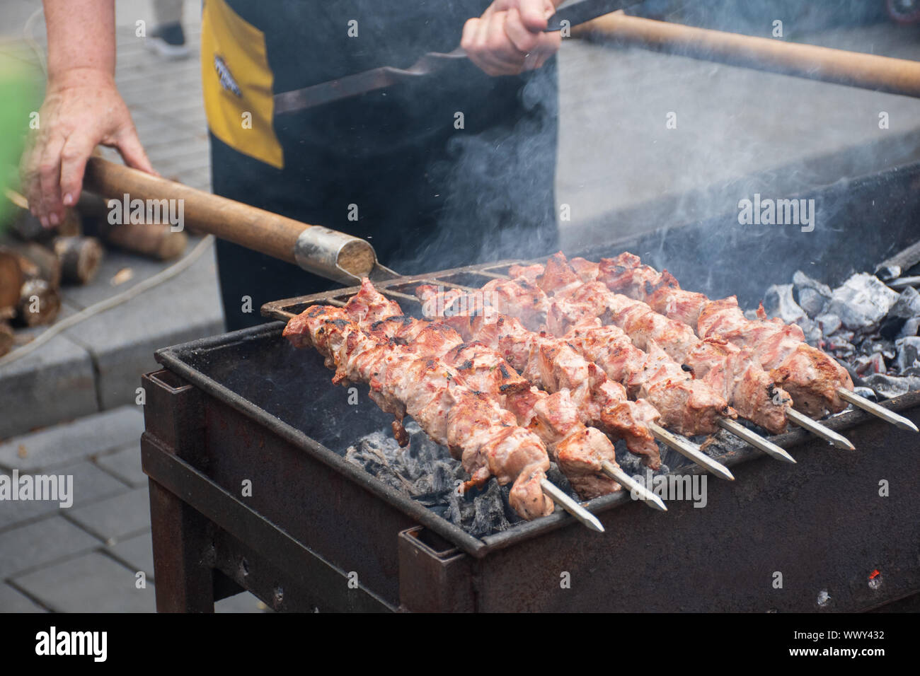Close up of  meat skewer, grilled in a barbecue, shashlik or shashlyk of pork for a pic nic, man preparing and roasting with pitchforks Stock Photo