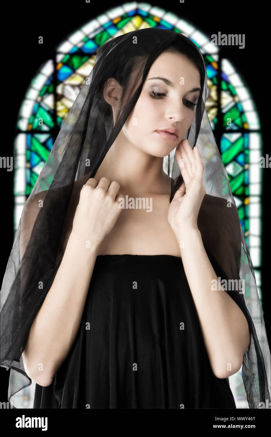 beautiful woman with a black veil on her head in a church like a ...