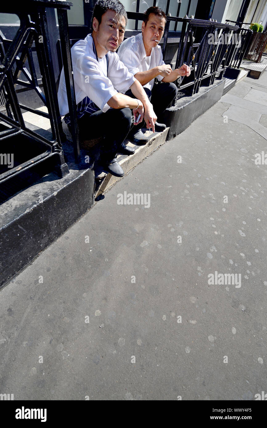 London, England, UK. Two Chinese restaurant workers having a cigarette break Stock Photo