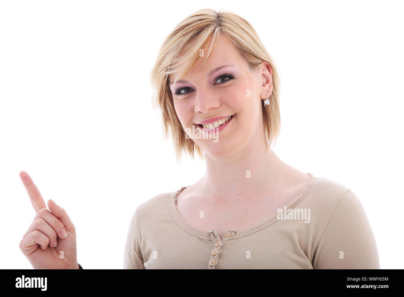 Attractive friendly smiling young saleslady pointing with her index finger to blank copyspace off frame at the left Stock Photo