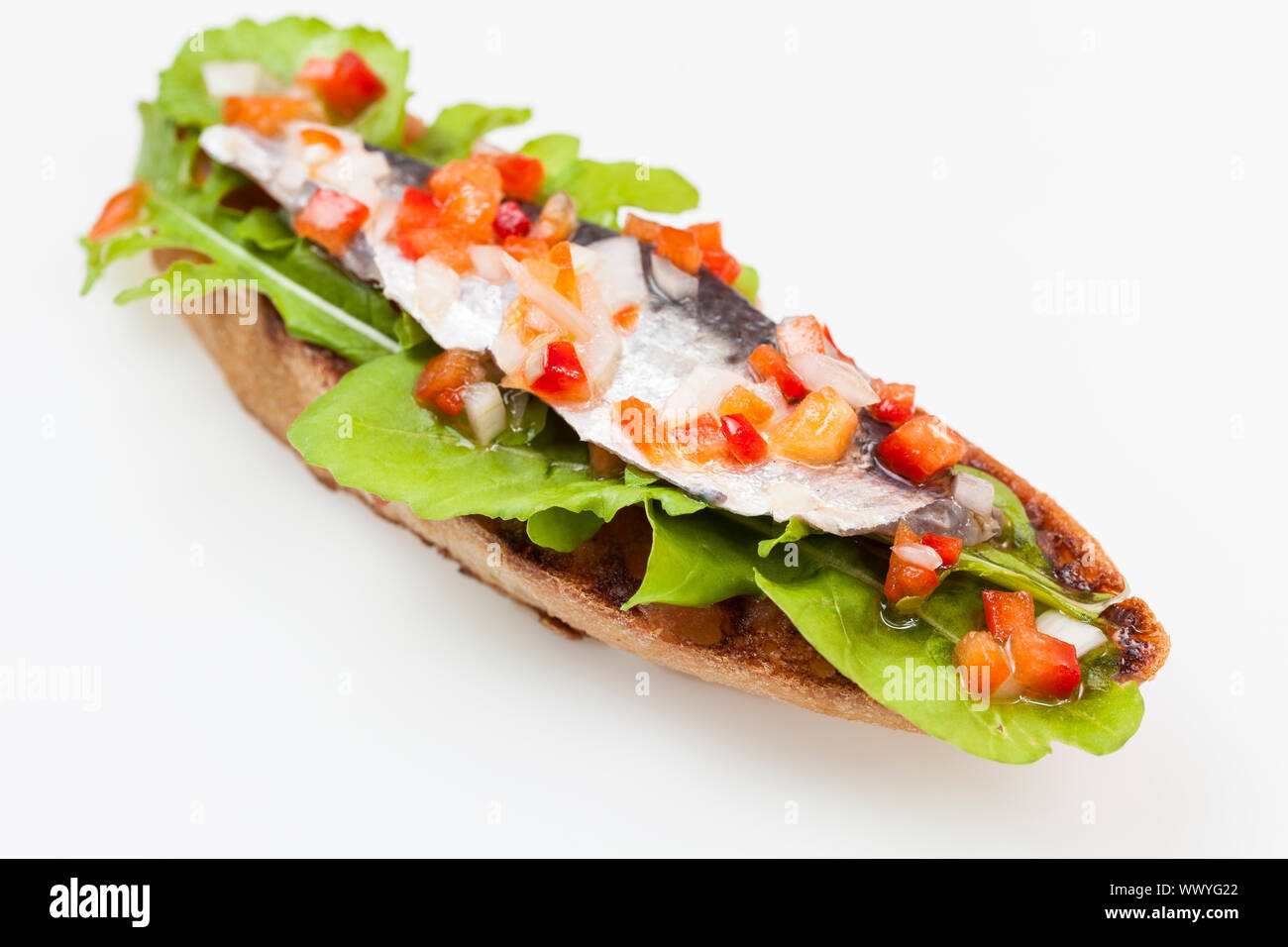 Slice of toast with marinade sardines, rocket salad, onion and red pepper Stock Photo