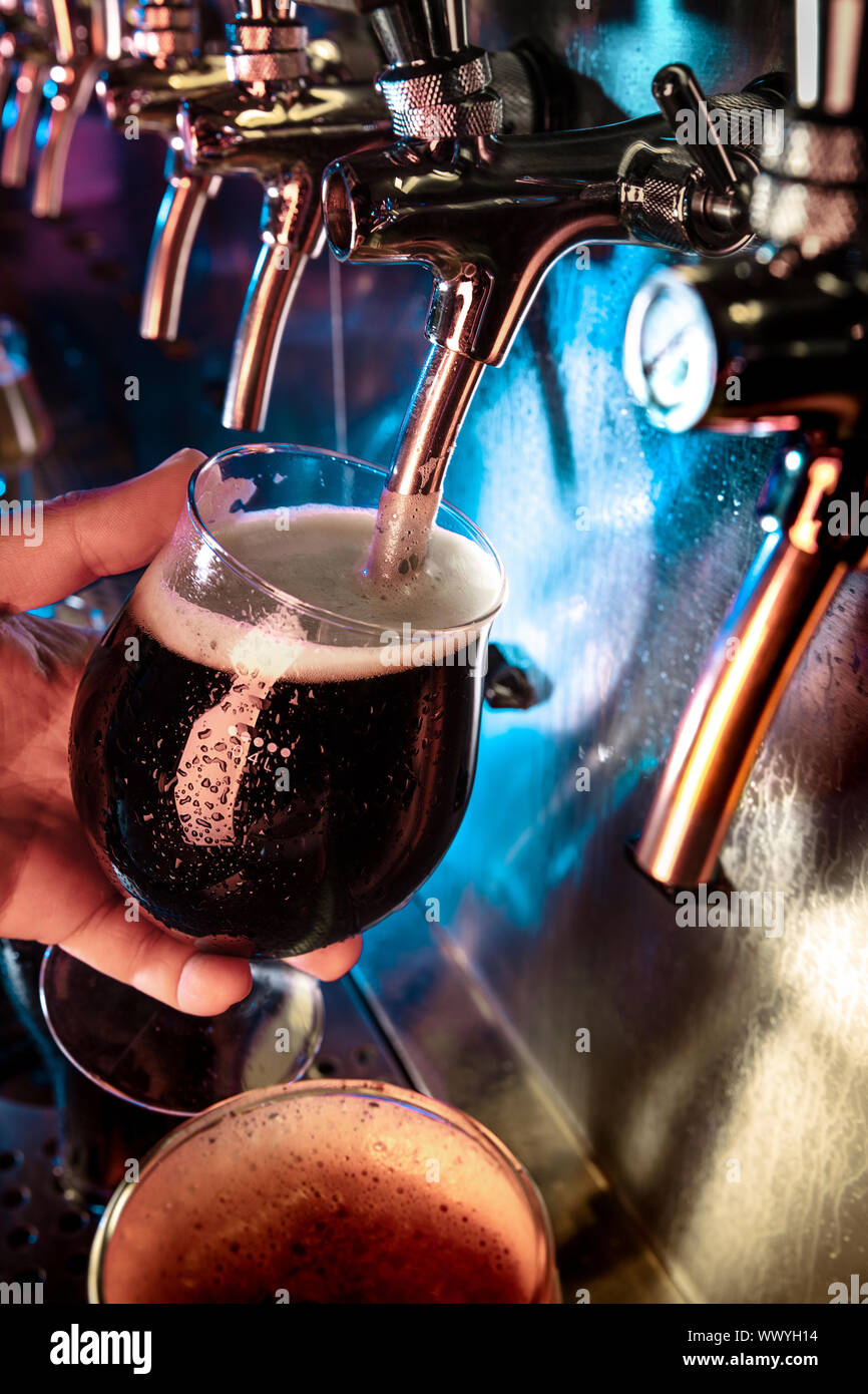 Hand of bartender pouring a large ale, porter, stout beer in tap
