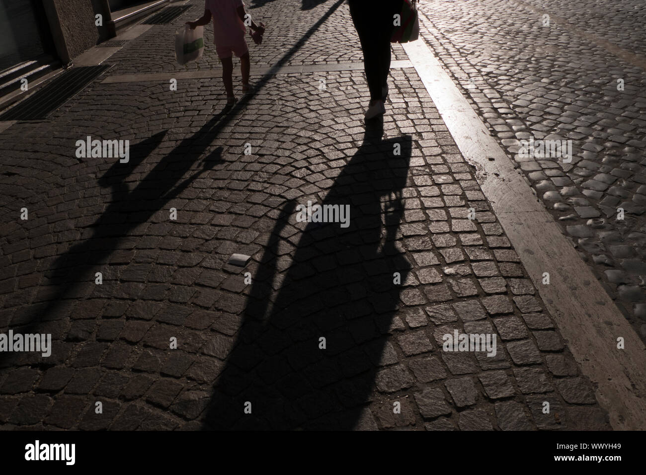 Shadows cast by Mother and daughter walking in the town of Tivoli in Italy Stock Photo