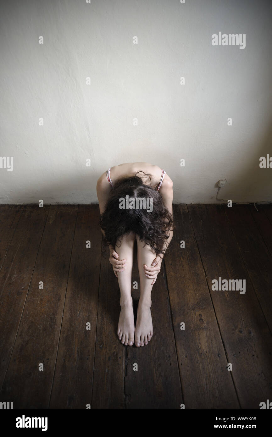 a desperate young woman is sitting on an old wooden floor. top view Stock Photo