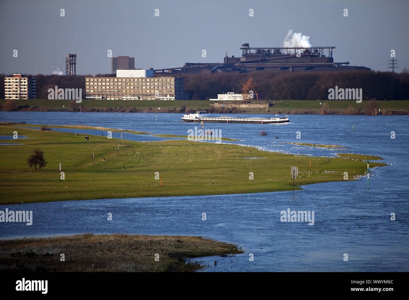 high water of river Rhine with cargo ship and Thyssenkrupp plant, Duisburg, Germany, Europe Stock Photo