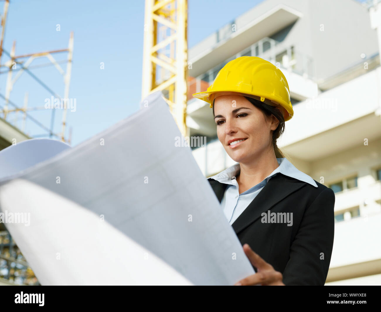 female engineer looking at blueprints in construction site Stock Photo