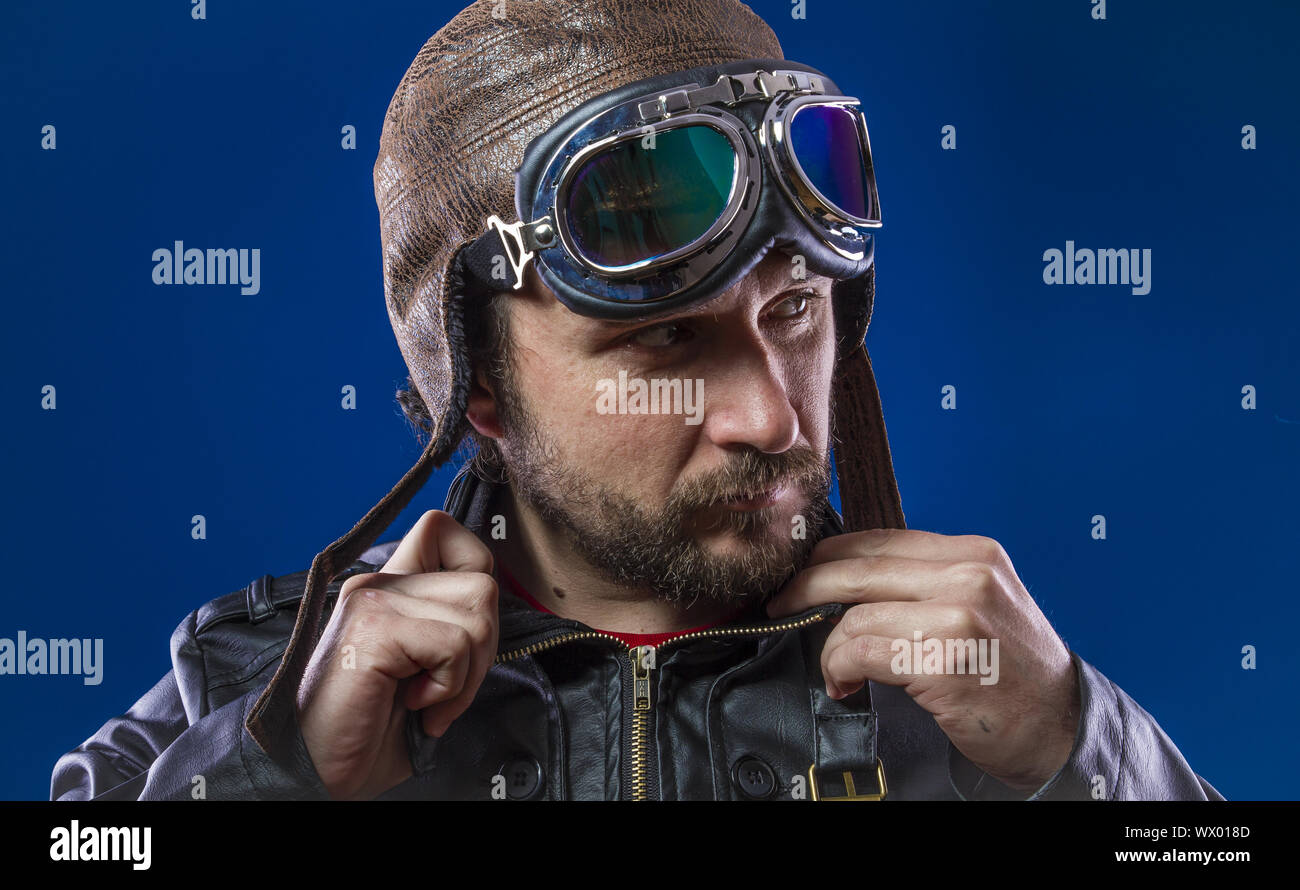 pilot of the 20s with sunglasses and vintage aviator helmet. Wears leather  jacket, beard and expressive faces Stock Photo - Alamy