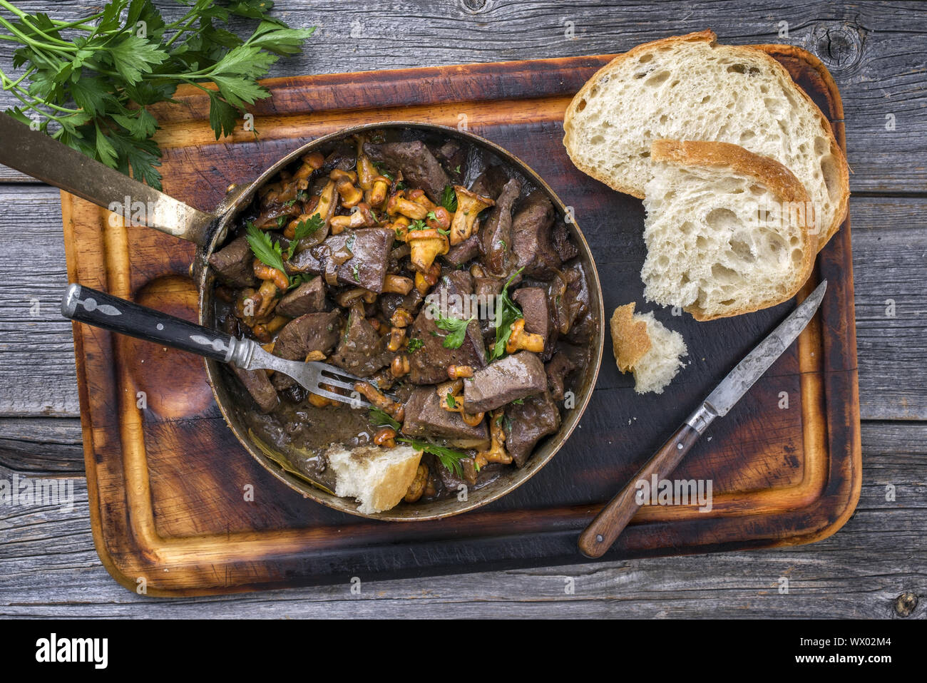 Fresh fried veal liver with chanterelle and baguette in sauce as top view in a casserole Stock Photo