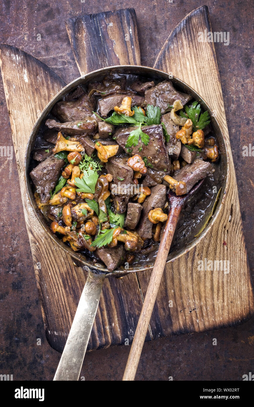 Fresh fried veal liver with chanterelle in sauce as top view in a