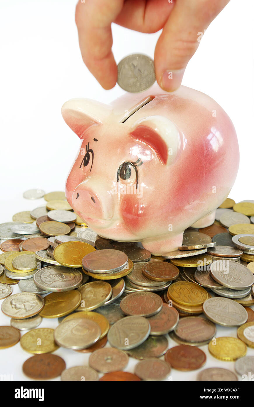 Hand inserting coin into piggy bank isolated on white Stock Photo - Alamy