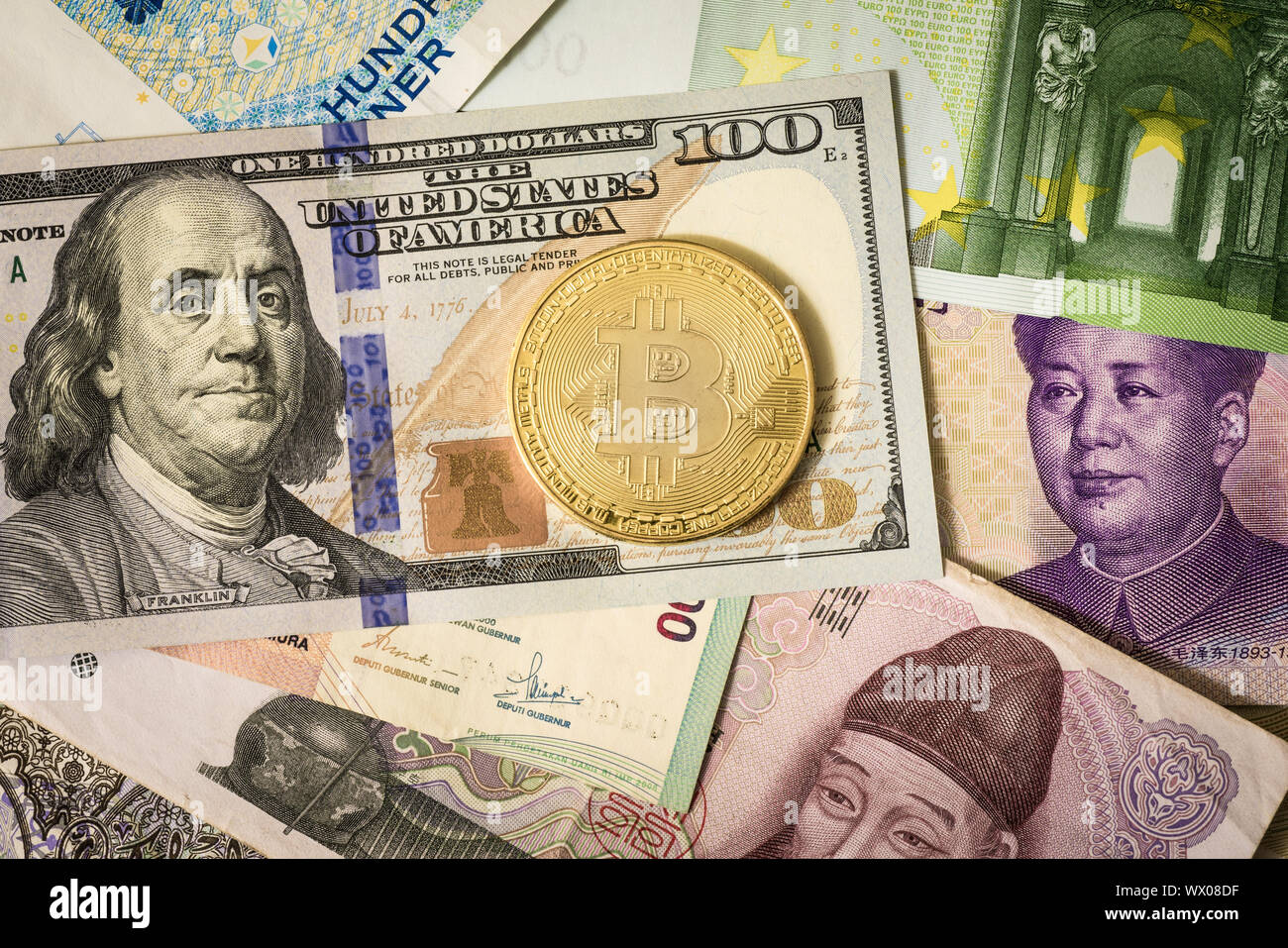 Golden bitcoin over multi currency banknotes dollar, yuan, euro Stock Photo