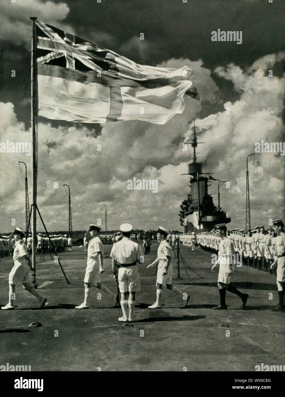 British sailors on the deck of an aircraft carrier, Second World War, c1943. The white ensign, which comprises a red St George's Cross on a white field with the Union Flag at top left, is flown on British Royal Navy ships and shore establishments. The Fleet Air Arm is the section of the Royal Navy responsible for the operation of naval aircraft. From &quot;Fleet Air Arm&quot;. [His Majesty's Stationery Office, London, 1943] Stock Photo