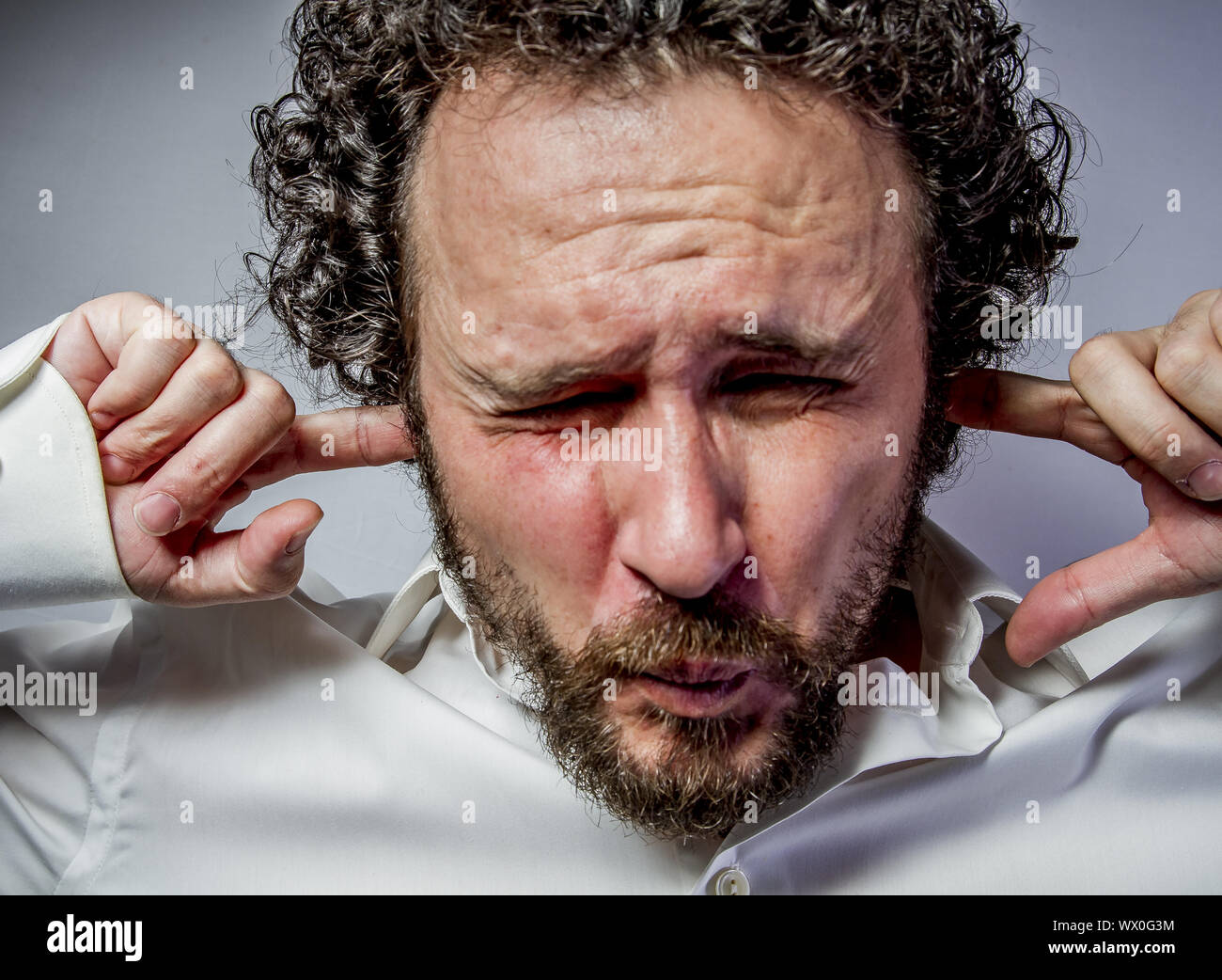 I do not want to hear anything, man with intense expression, white shirt Stock Photo