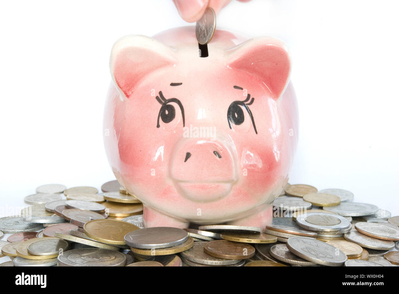 Hand inserting coin into piggy bank isolated on white Stock Photo - Alamy