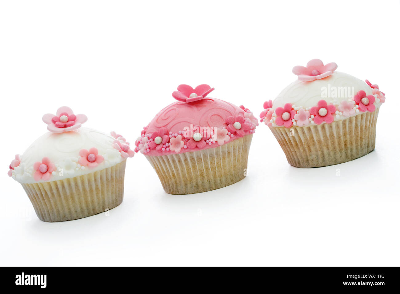 Three pink and white cupcakes against a white background Stock Photo