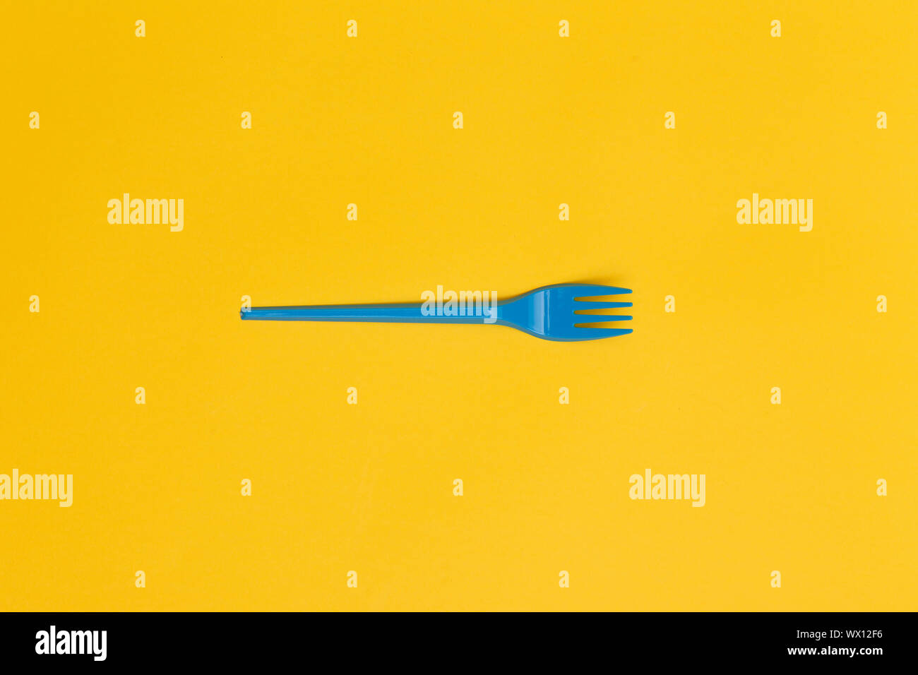 Single blue disposable fork over a yellow background. Stock Photo