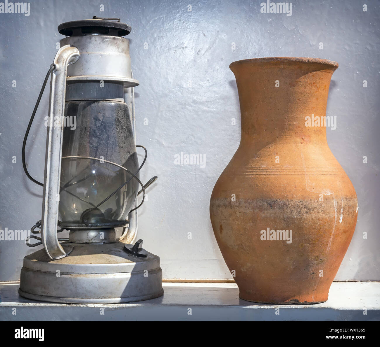 Antique objects of everyday life: a kerosene lamp and a pitcher. Stock Photo