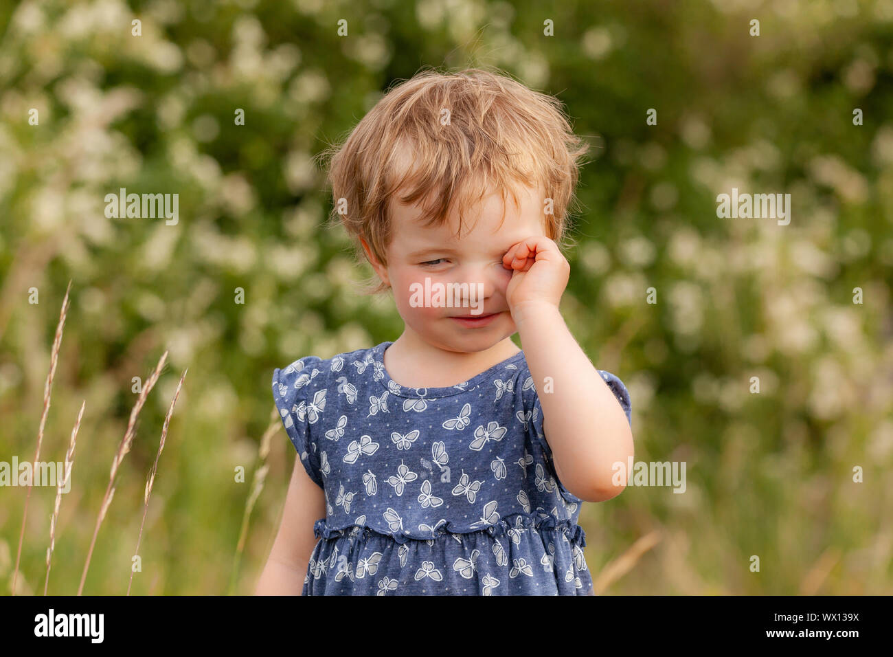 Tired child rubs his eyes Stock Photo
