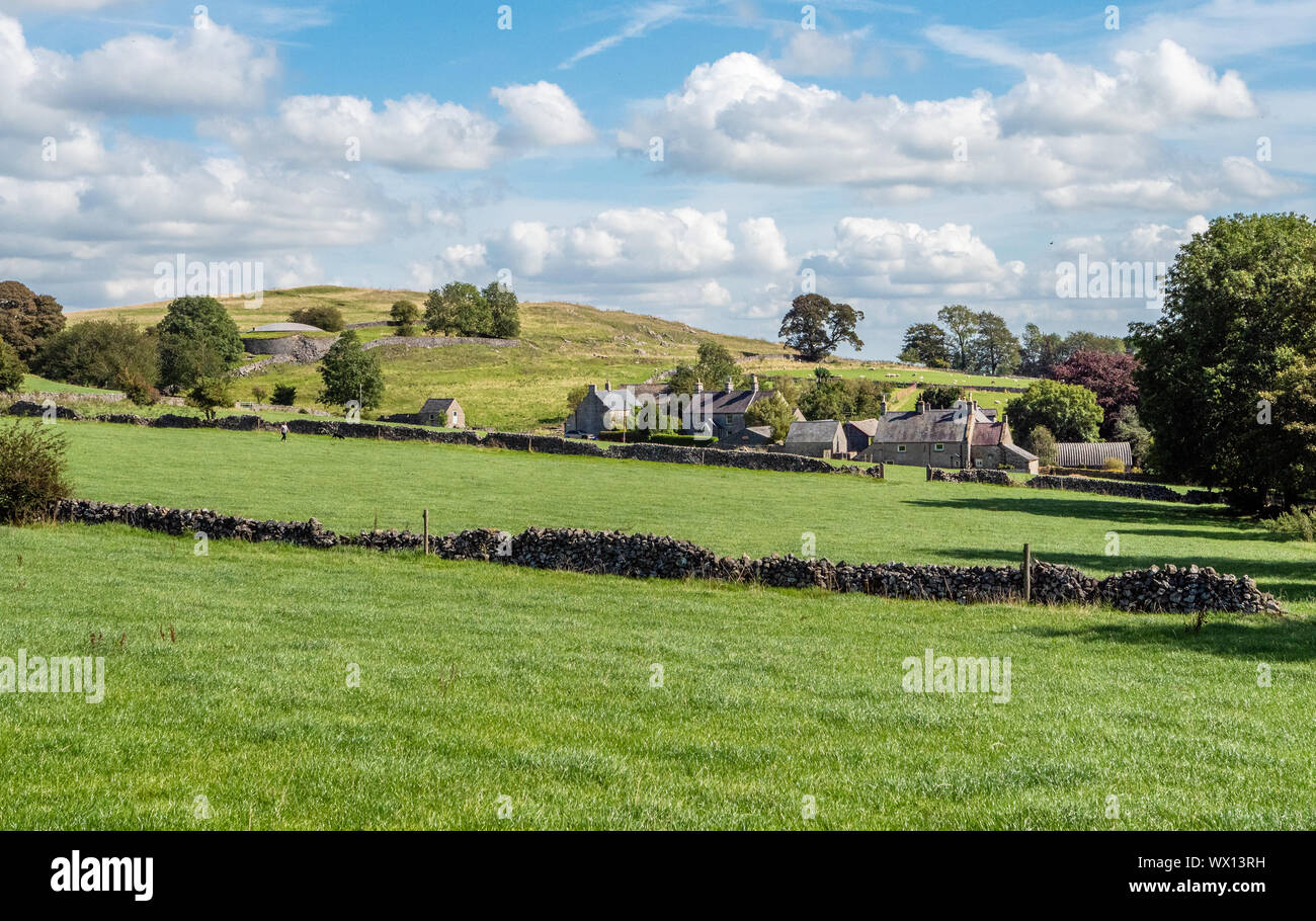 The hamlet of Rowdale nestled beneath its hill and circular reservoir near Bakewell in the Derbyshire Peak District UK Stock Photo