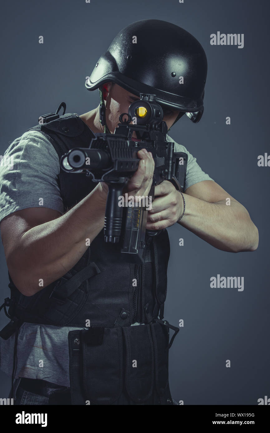 Safety, paintball sport player wearing protective helmet aiming pistol ,black armor and machine gun Stock Photo