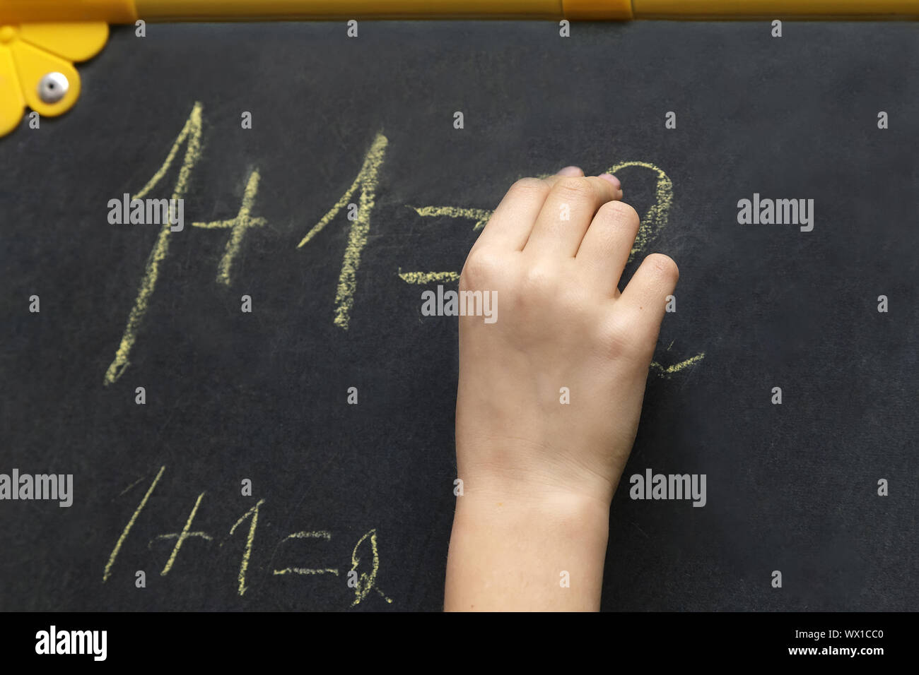 The girl writes in chalk on the blackboard. Stock Photo
