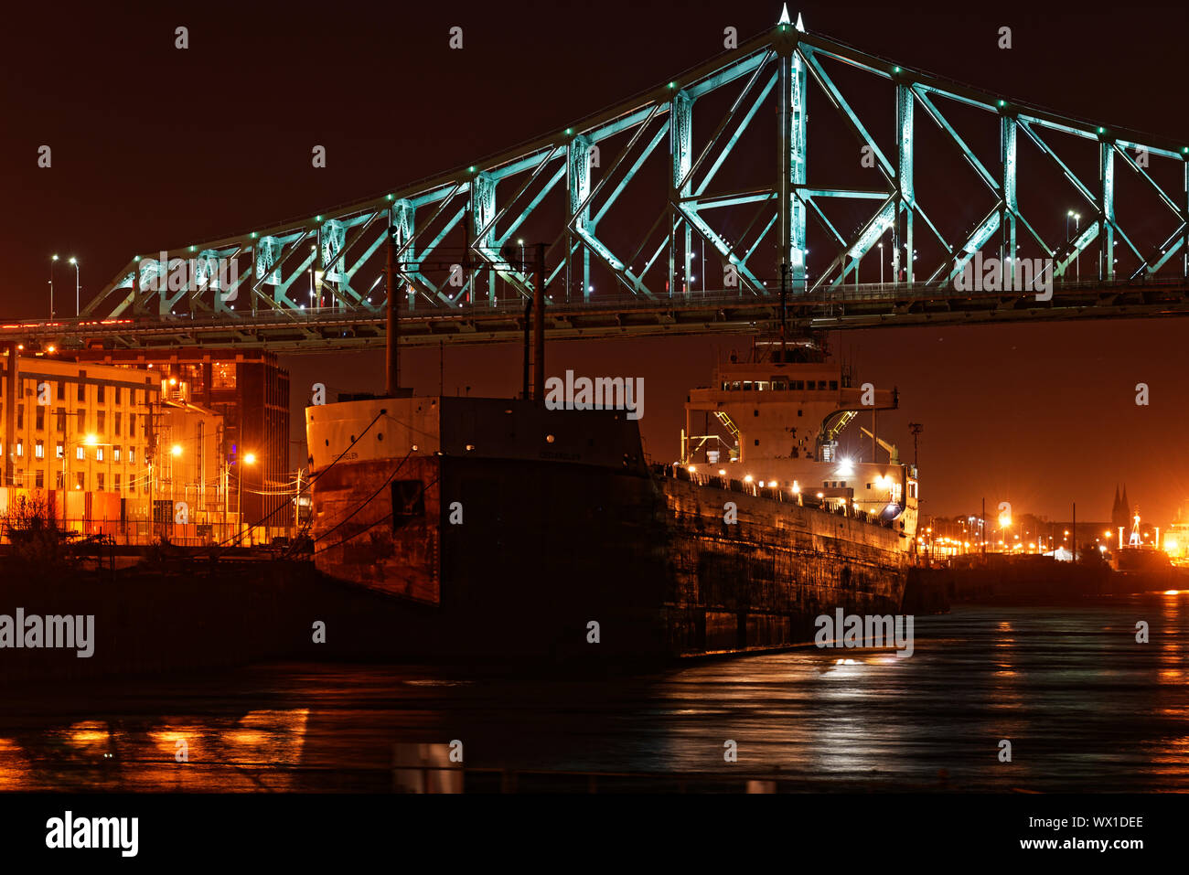 A cargo ship moored under Montreal Harbour Bridge at night Stock Photo