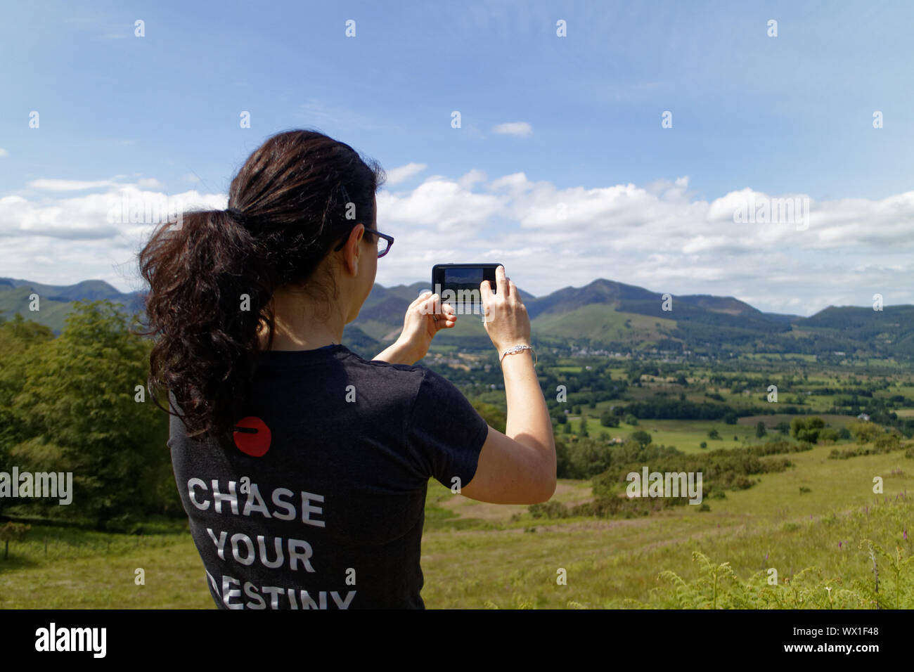 A woman taking photos in the Lake District using her cell phone Stock Photo