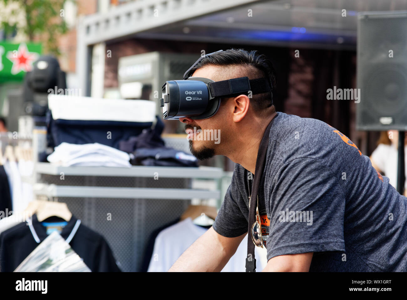 A man wearing virtual reality goggles and riding a motorcycle simulator Stock Photo