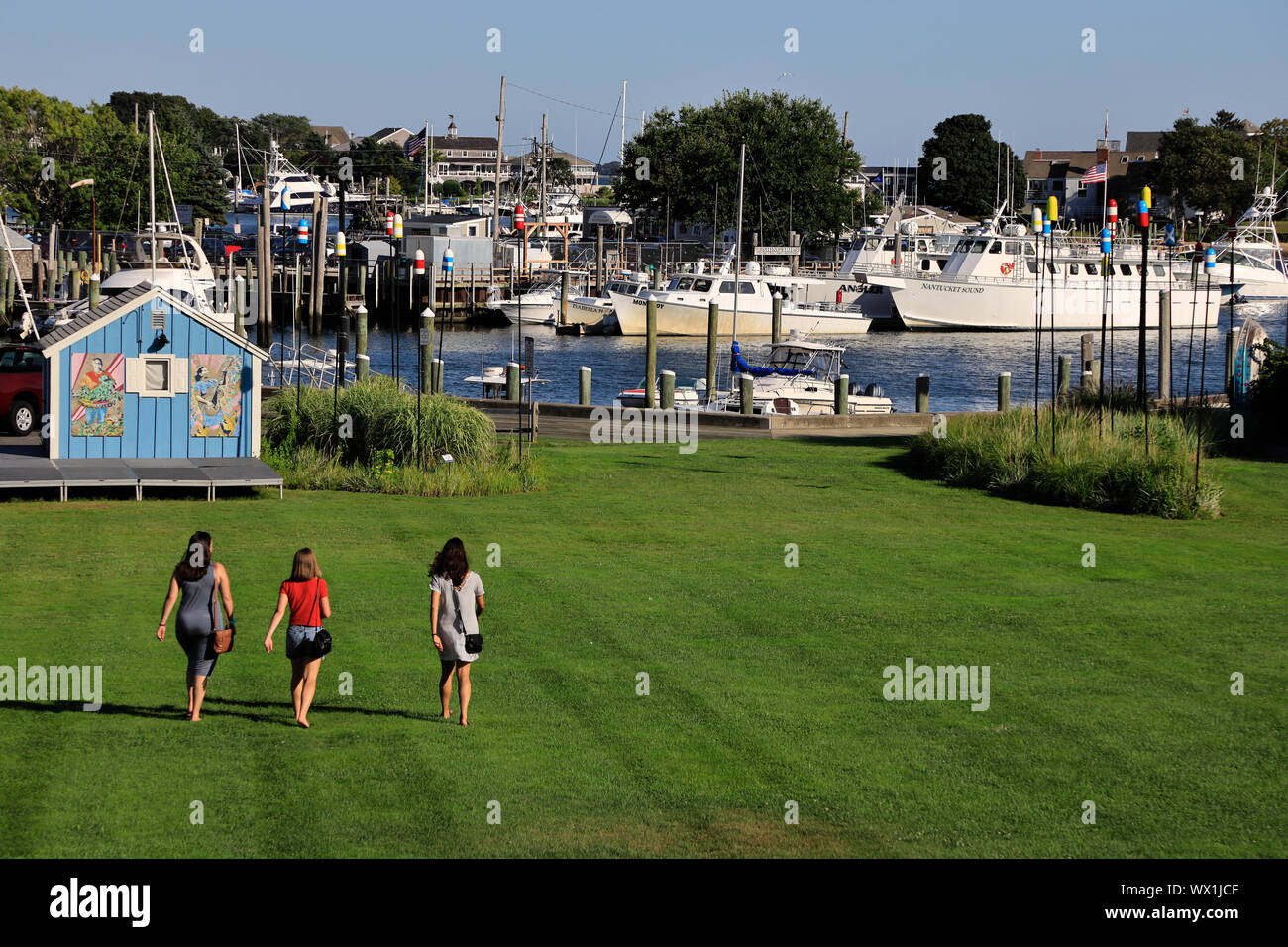 The view of Hyannis harbor with three young females walking towards it in foreground.Hyannis.Massachusetts.USA Stock Photo