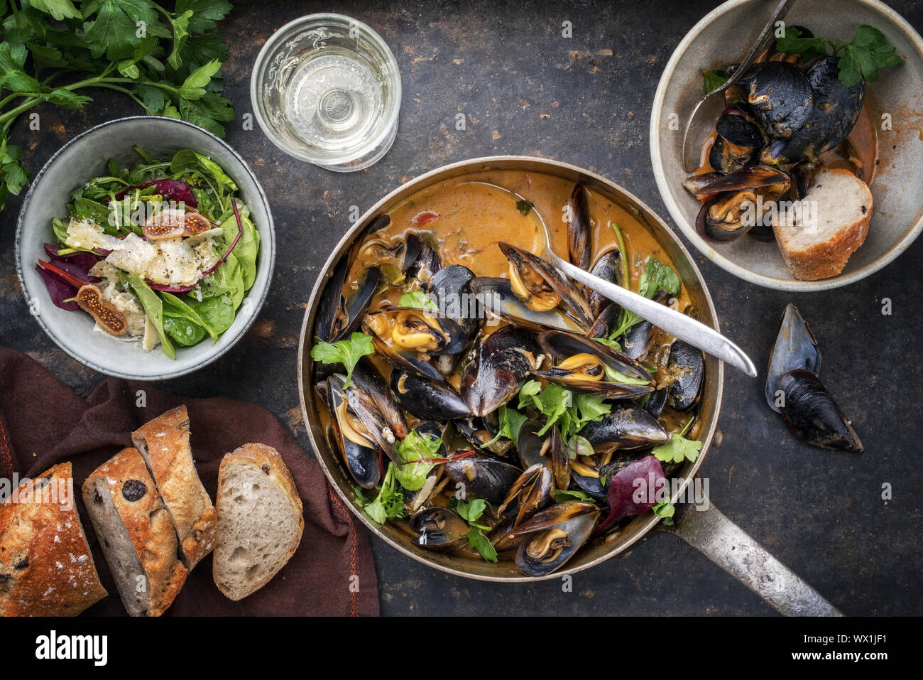 Traditional French blue mussel in bouillabaisse with lettuce and baguette as top view in a casserole Stock Photo