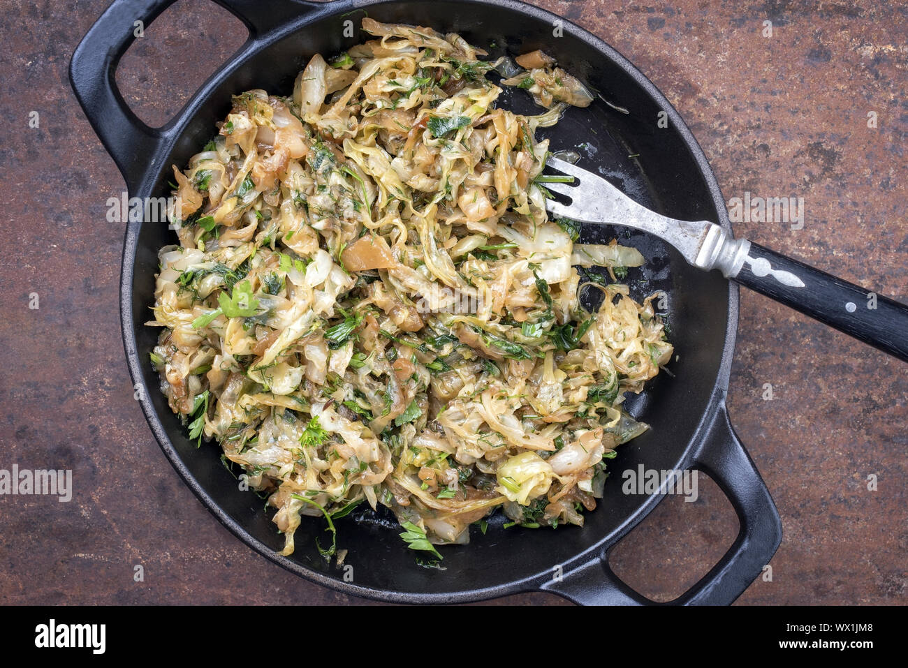 Fresh fried white cabbage as top view in a cast iron pan Stock Photo