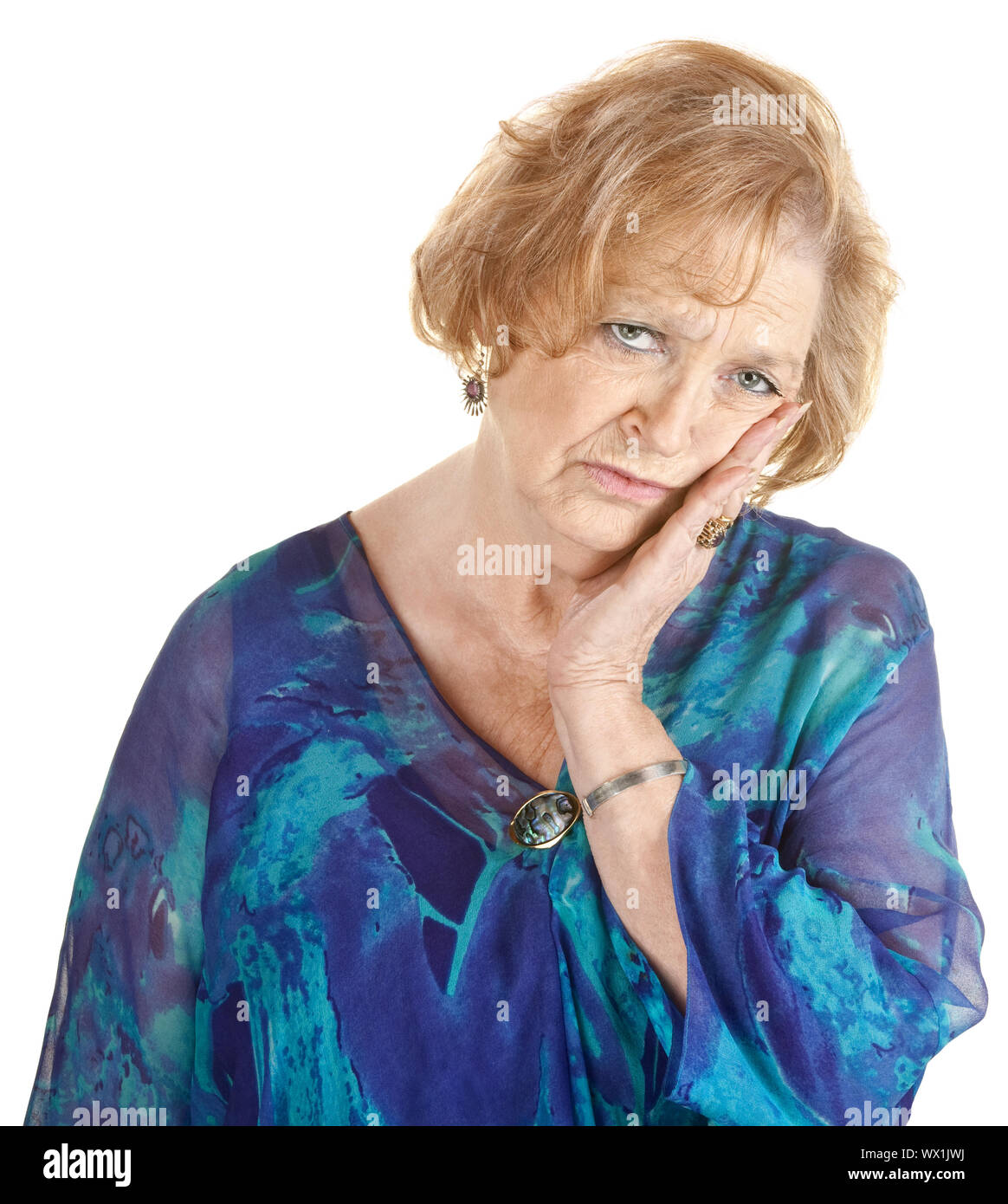 Tired older woman in blue with hand on cheek Stock Photo - Alamy