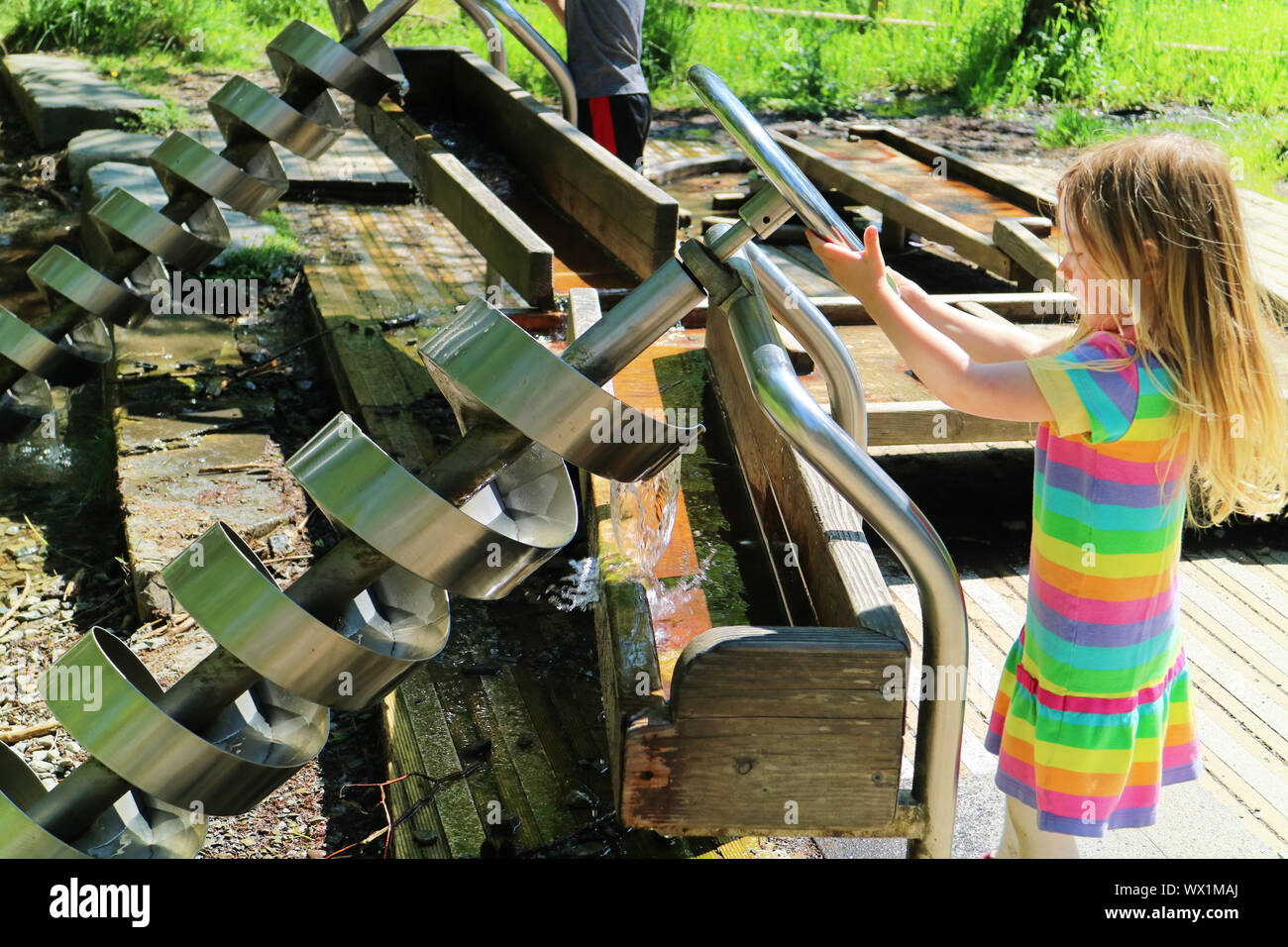 A little girl operating an Archimedes Screw at Whinlatter in the Lake District, Cumbria, UK Stock Photo