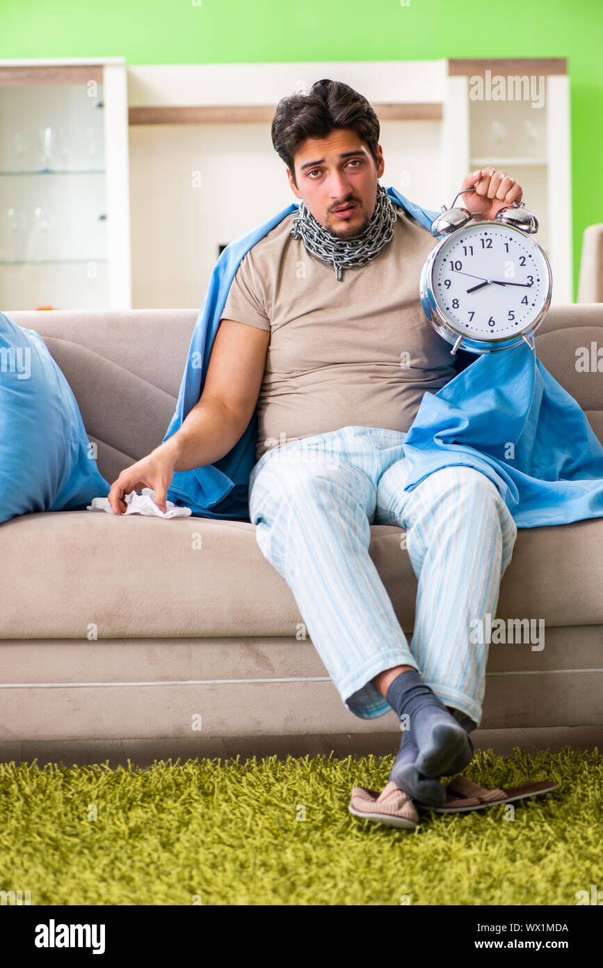 Sick young man suffering from flu at home in time management con Stock Photo