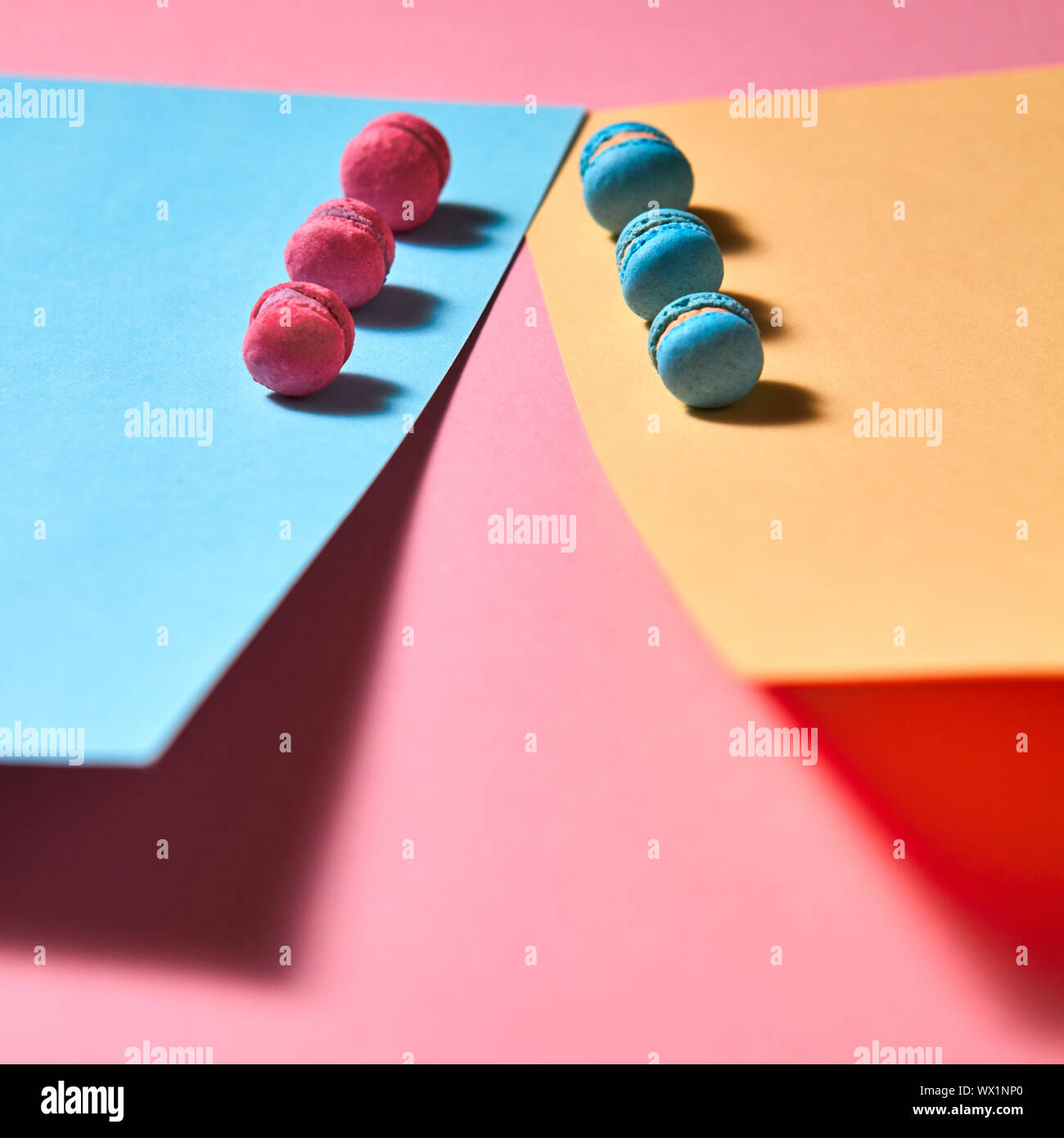 Different macaroons presented in a row on a colored paper background Stock Photo