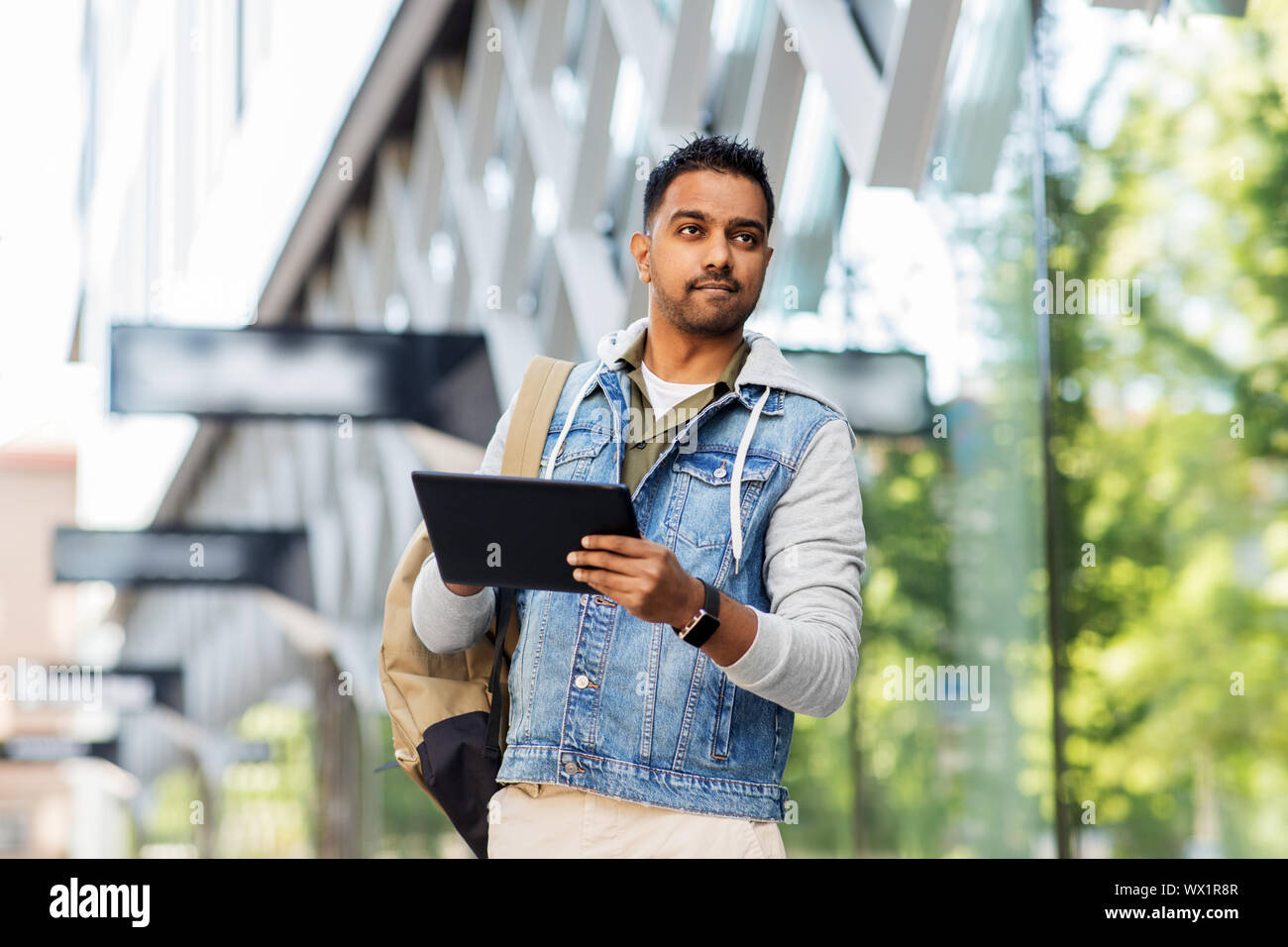 man with tablet pc and backpack on city street Stock Photo