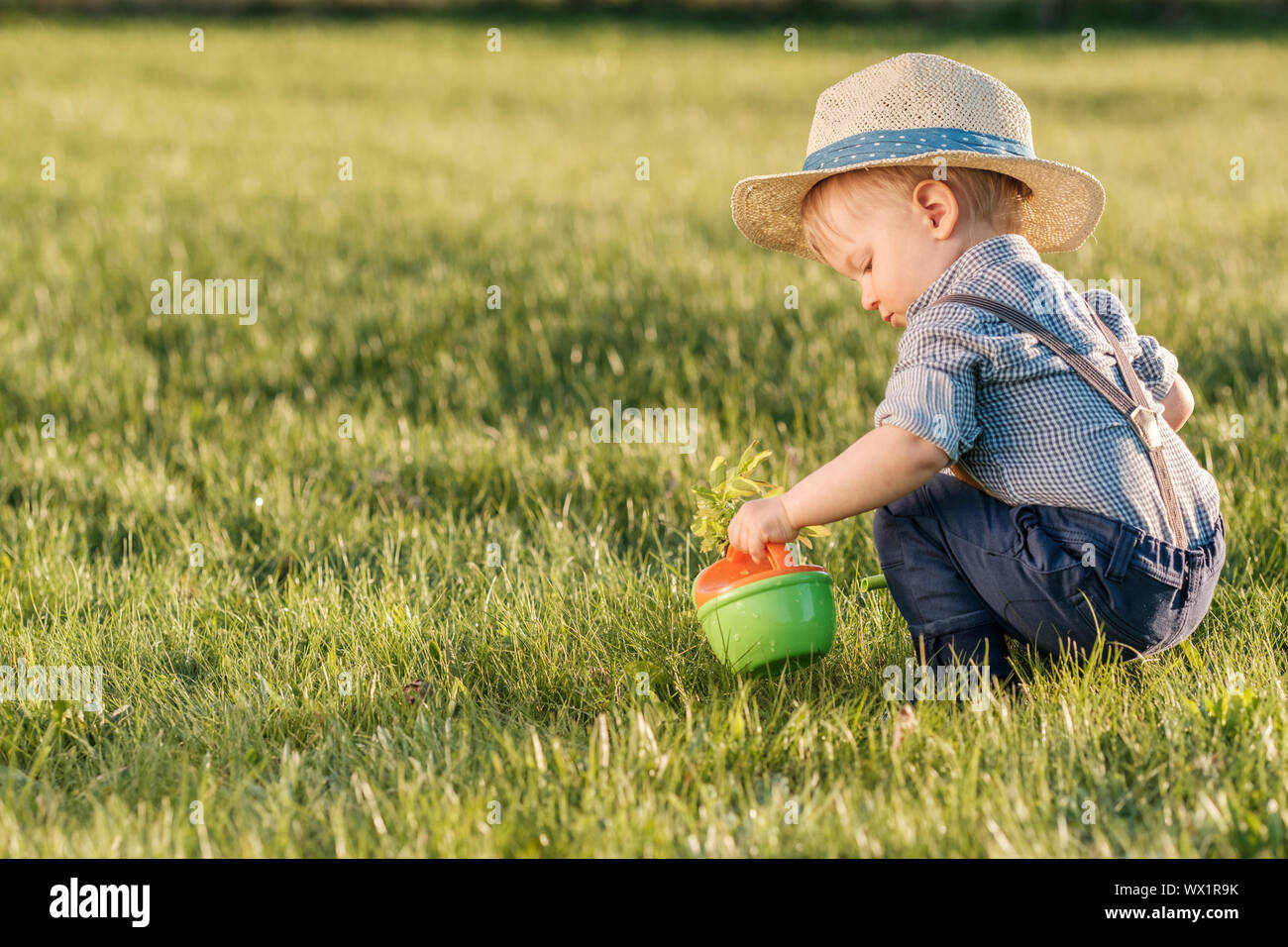 Toddler child outdoors. One year old baby boy wearing straw hat using