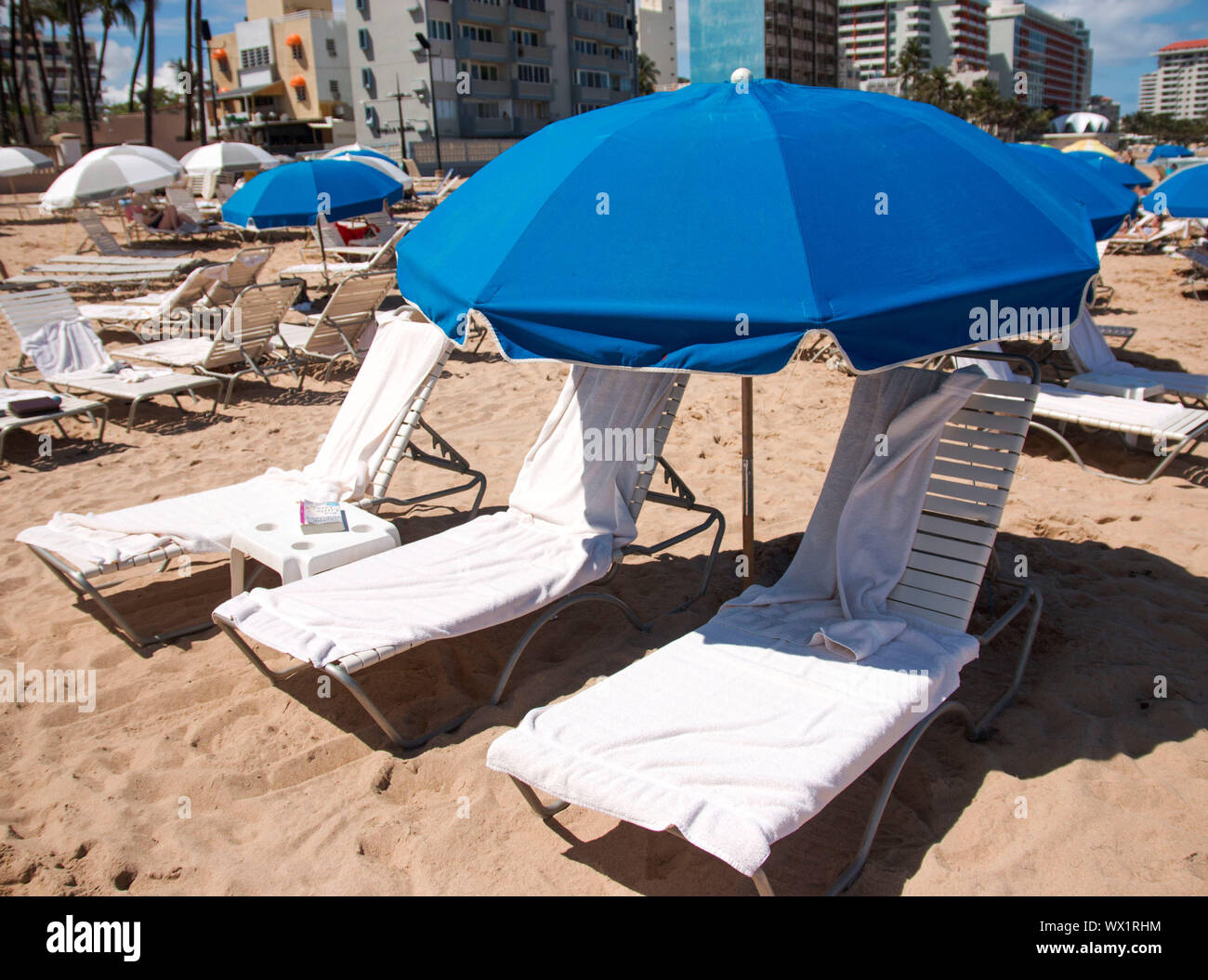 beach chairs and blue umbrellas are set up on a beach in Condado Puerto Rico Stock Photo