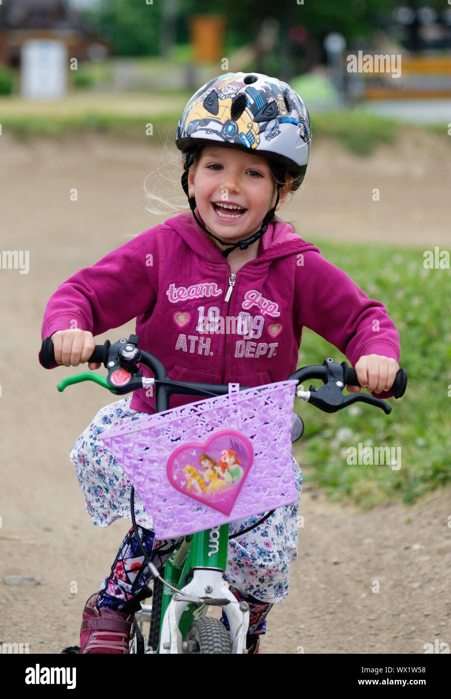 A little girl (5 yrs old) beaming with joy as the rides her bike Stock Photo