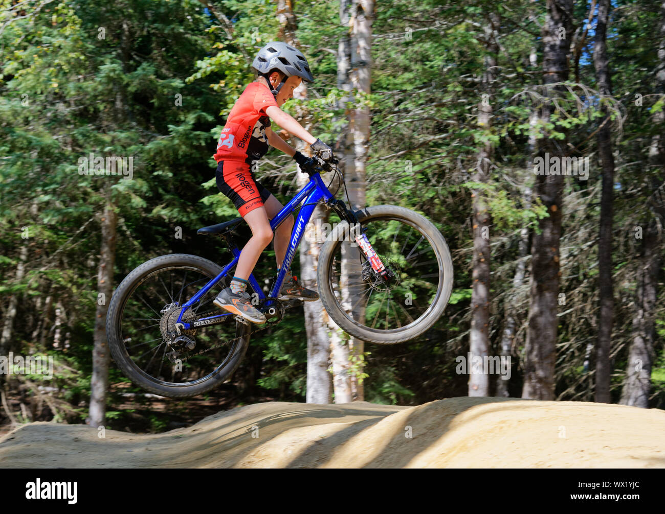 A seven year old boy doing jumps on his mountain bike Stock Photo